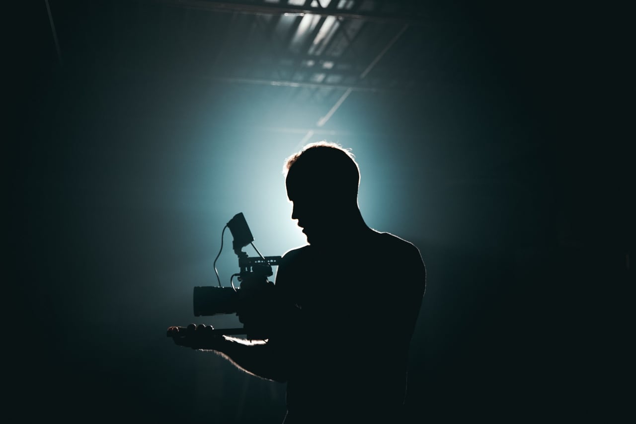 Camera operator filming in a studio with directional light