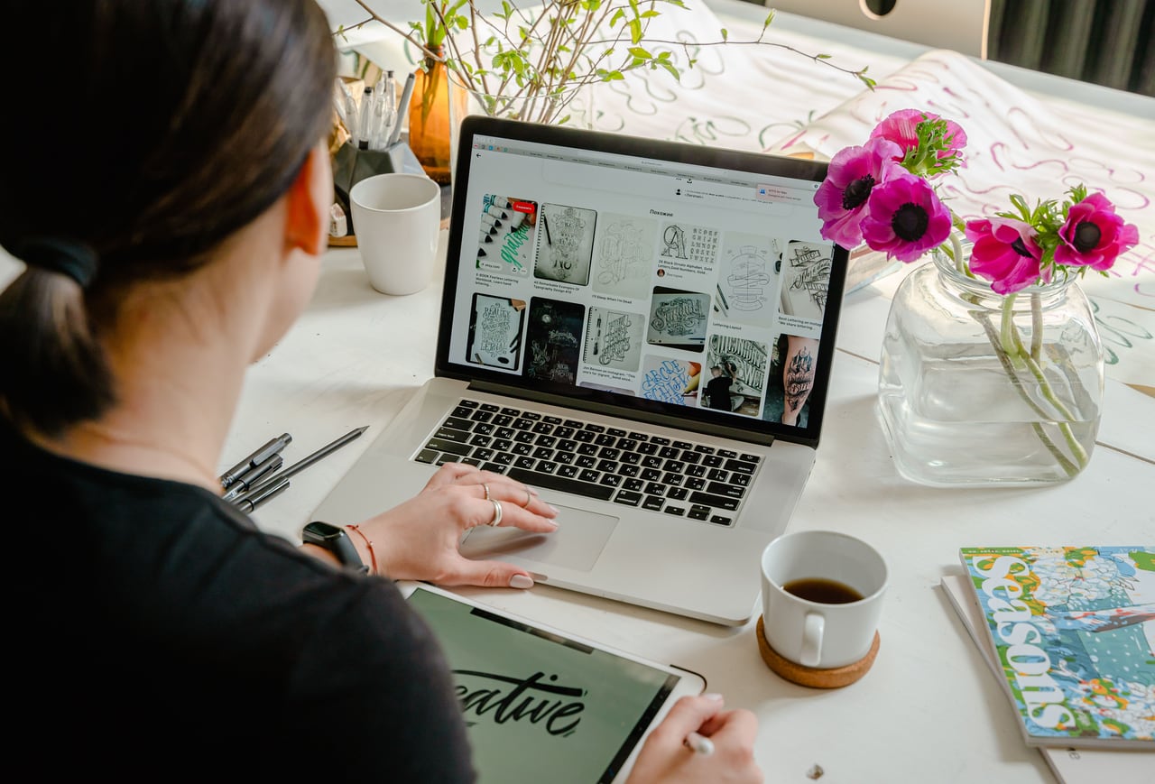 Designer using a laptop and drawing tablet at a creative workspace