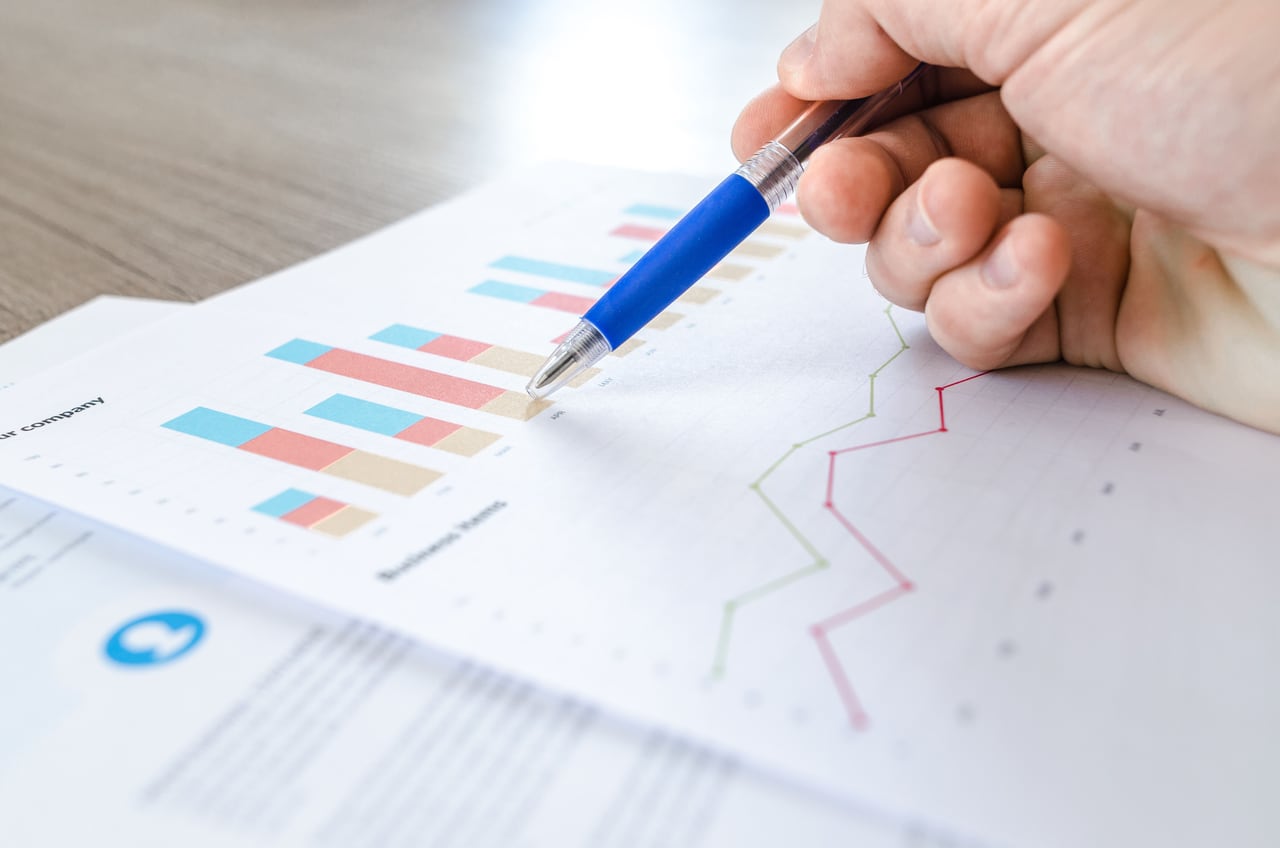 Hand reviewing charts and performance figures on paper