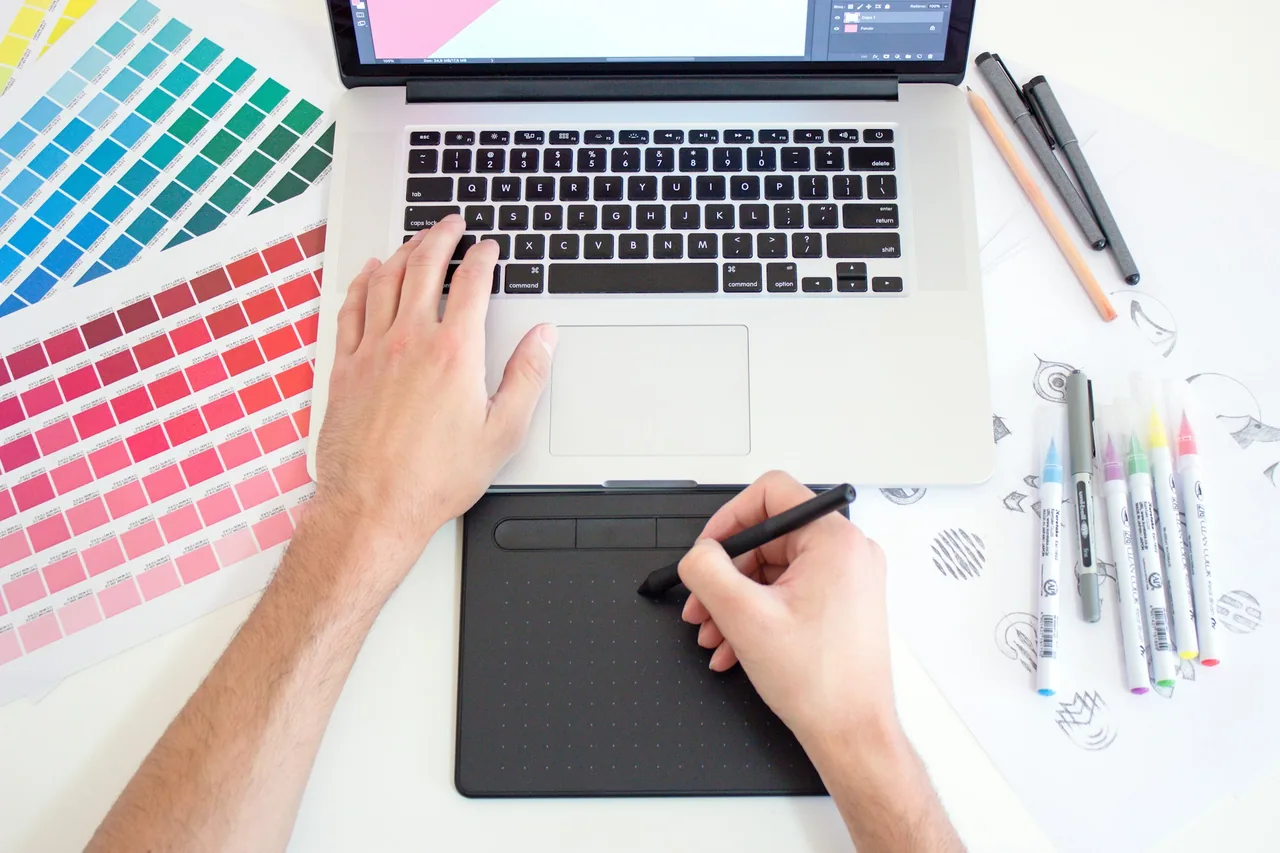 Designer working with a drawing tablet, laptop and color swatches
